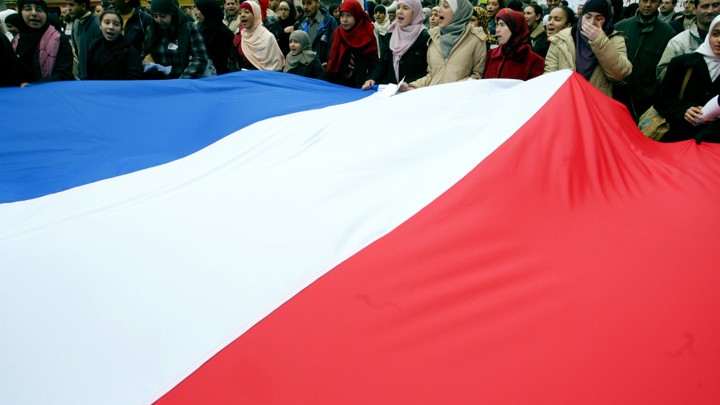 Women wearing head scarves carry the French national flag during a demonstration.