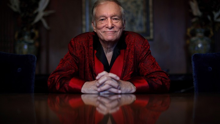 Hugh Hefner sits at a table.