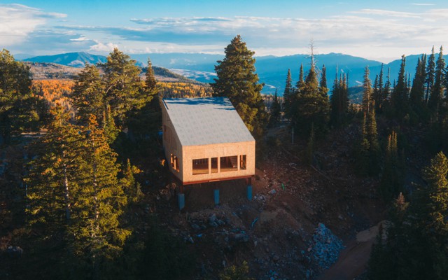 An unfinished house with a slanted roof on a mountain among trees