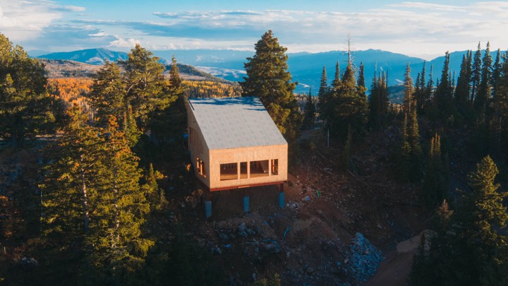 An unfinished house with a slanted roof on a mountain among trees