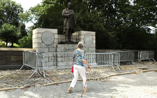 A woman with a cane walks past the J Marion Sims statue in New York's Central Park.