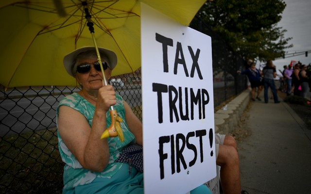 A woman holds a sign during demonstrations as U.S. President Donald Trump delivers a speech on tax reform.