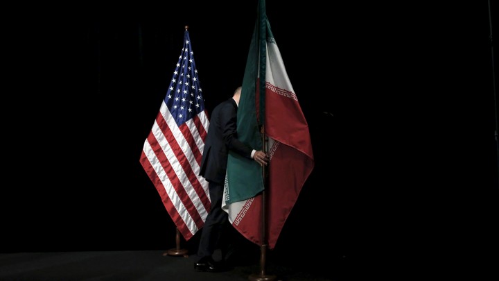 A staff member removes the Iranian flag from the stage next to the American flag.