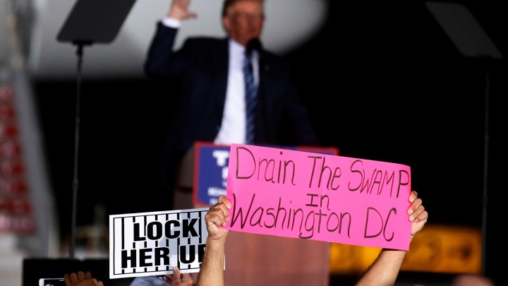 Trump supporters hold up a "Drain the Swamp" sign.