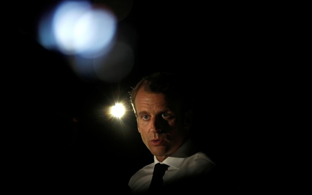 President Emmanuel Macron talks with lights in the background.