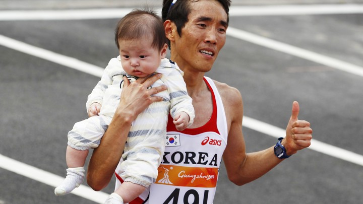 Ji Young-jun poses with his baby after winning the men's marathon at the 16th Asian Games.
