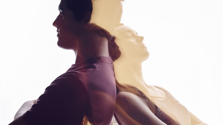 A boy and girl stand back to back.