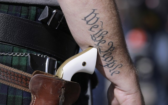 A man wears a pistol as he prepares for a rally in support of open-carry gun laws. 