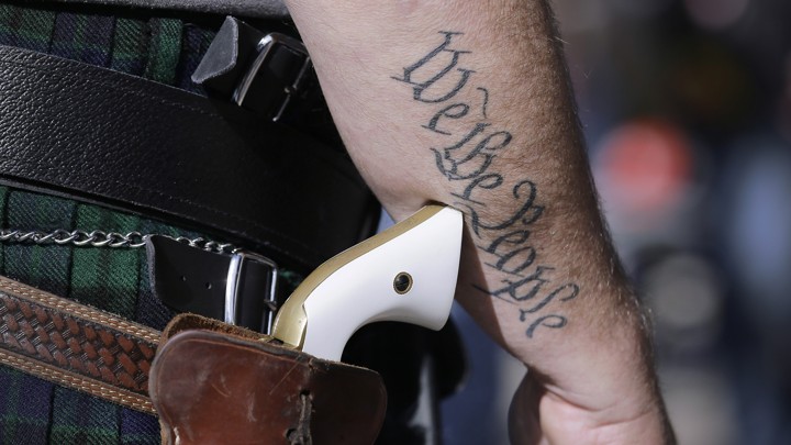 A man wears a pistol as he prepares for a rally in support of open-carry gun laws.