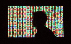 Shadow of a person's head in front of a screen showing DNA