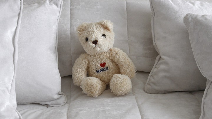A teddy bear on a bed surrounded by pillows