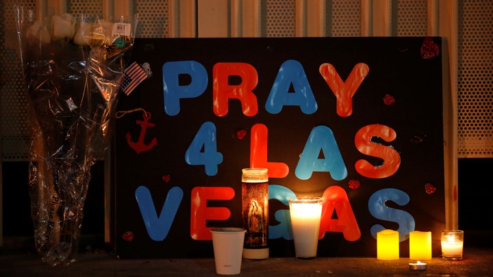 A poster next to flowers and candles reads, "Pray 4 Las Vegas"