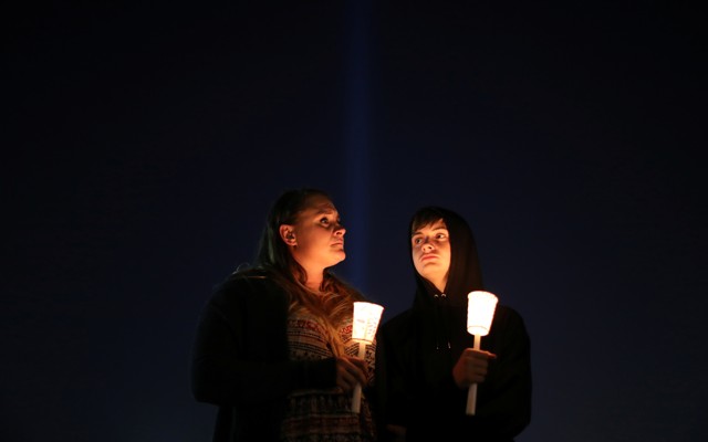 People hold candles at a vigil.