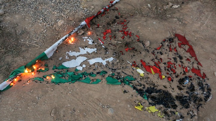 A burnt Kurdistan flag lying in the dirt.