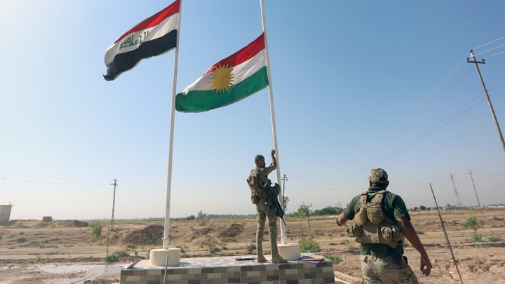 An Iraqi soldier takes down a Kurdish flag in Kirkuk