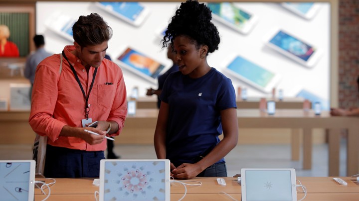 An Apple Store employee assists a customer.