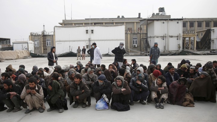 People sit on the ground surrounded by doctors and police officers.