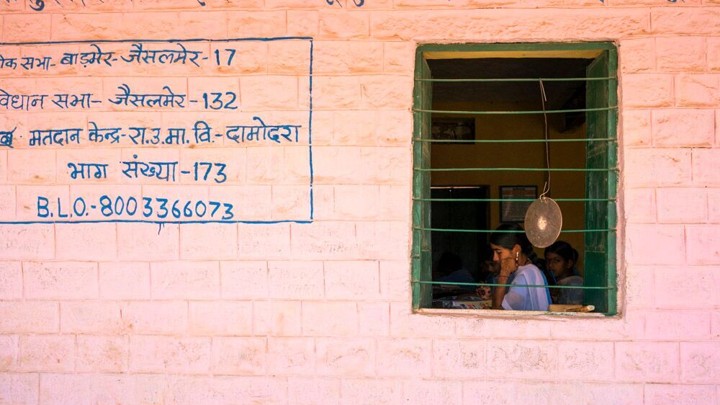 Students are seen studying through the window of a building.