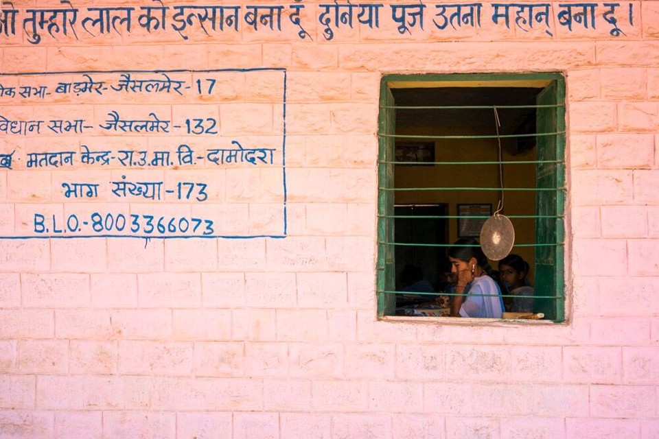 Students are seen studying through the window of a building. 