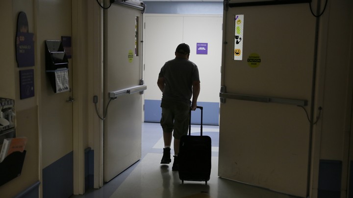Man walking through hallway with suitcase