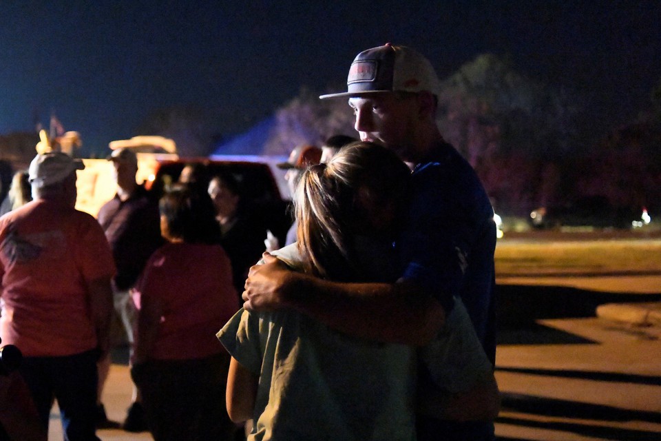 Two people embrace at a nighttime vigil.