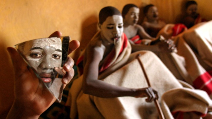 South African boys in traditional clothing and with white-painted skin sit in a classroom