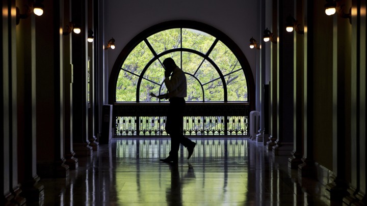 An unidentifiable man walks with a cellphone through a Capitol Hill building.
