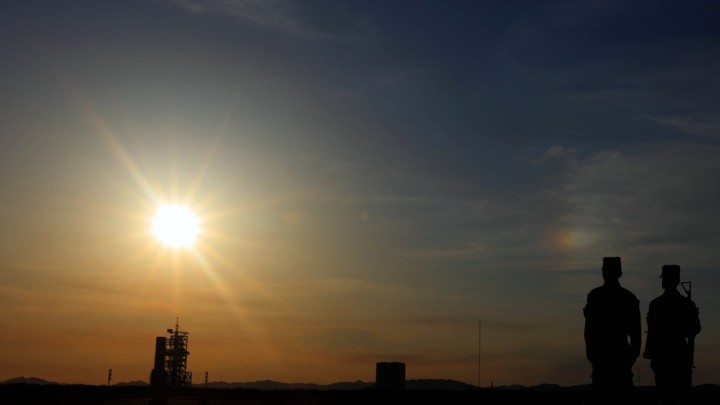 Soldiers in silhouette guard a space launch site.