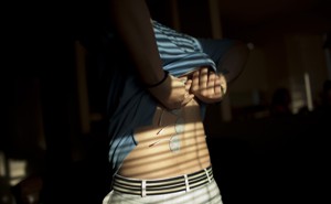 A person applies electrical stimulation pads to their back.
