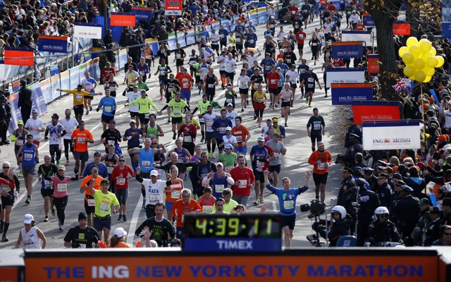 Runners approach the New York City Marathon finish line, where a clock reads 4:39:11