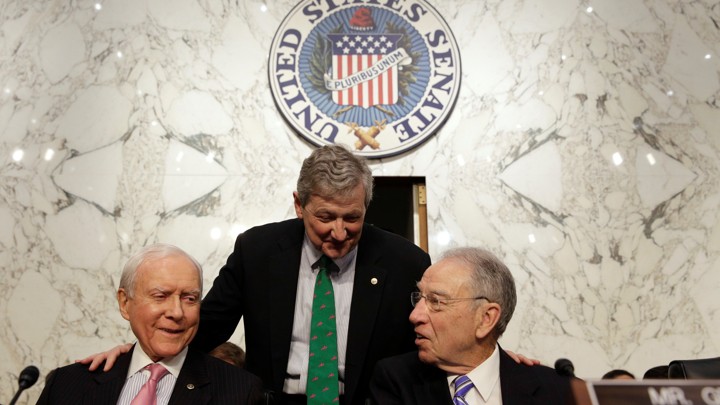 Senator John Kennedy (standing) speaks with Senators Orrin Hatch (left) and Chuck Grassley.