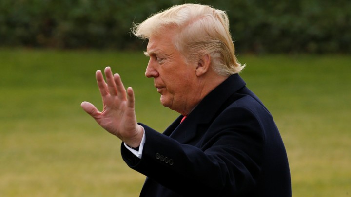 President Trump raises his hand toward a camera.