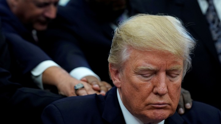 Faith leaders place their hands on the shoulders of U.S. President Donald Trump.