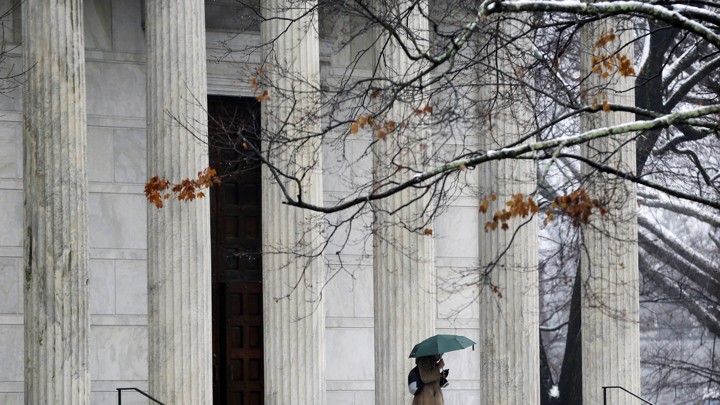 A person with an umbrella walks outside on the Princeton University campus.