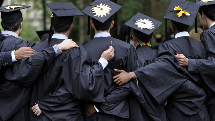 College graduates are shown from behind, with arms around each other