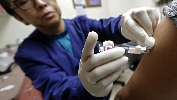 A health worker injecting a flu shot into a patient's arm