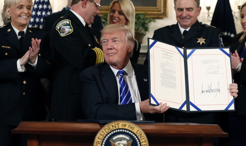 President Trump holds a signed bill in at the White House.