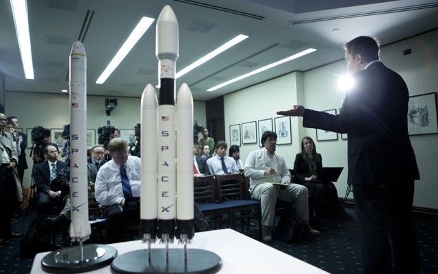 A person gestures to two models of rockets labeled "SpaceX."