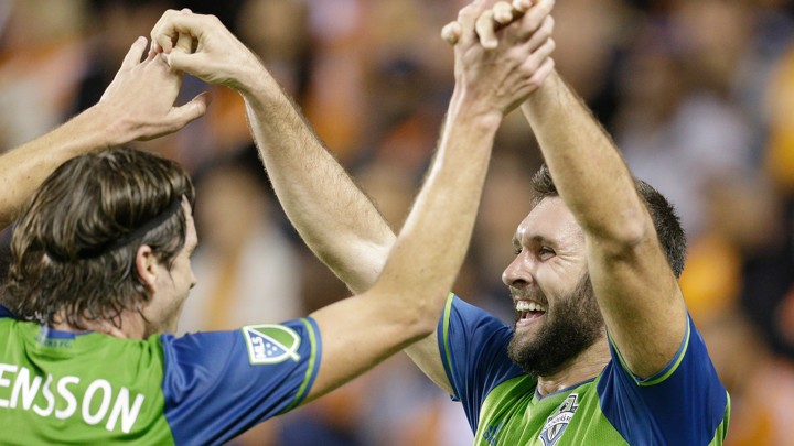 Will Bruin and Gustav Svensson exchange a high-five in their soccer uniforms.
