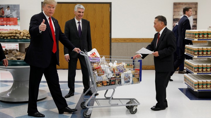 President Donald Trump pushes a shopping cart while giving a thumbs-up.