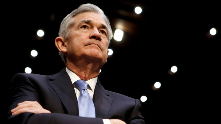 Jerome Powell looking up with arms crossed