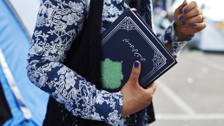 A Muslim refugee holds a Koran in Lesbos, Greece