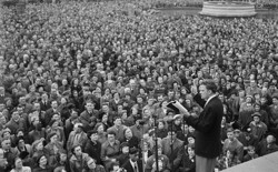 Evangelist Billy Graham, on stage, addresses a crowd.