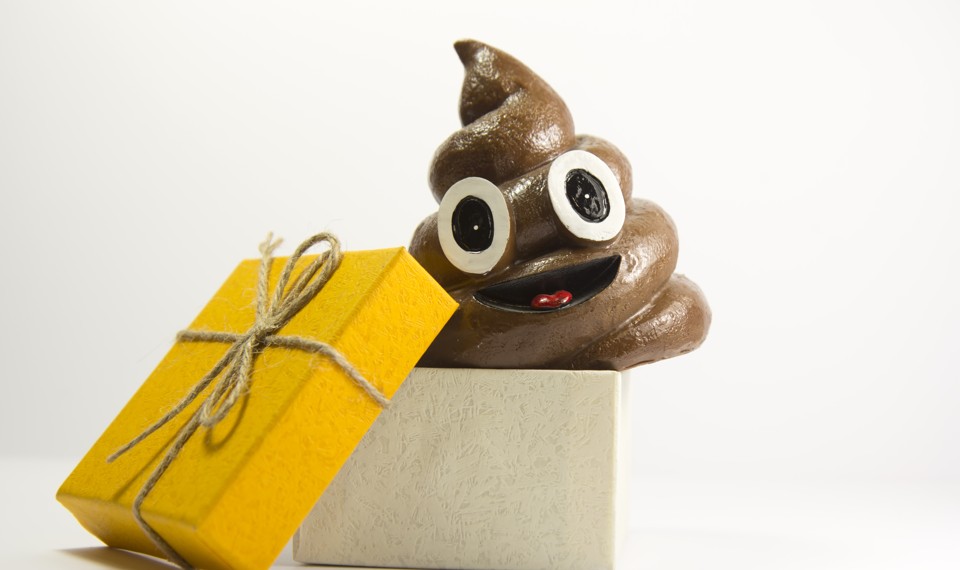 A smiling, cartoonish pile of poop next to a gift-wrapped box