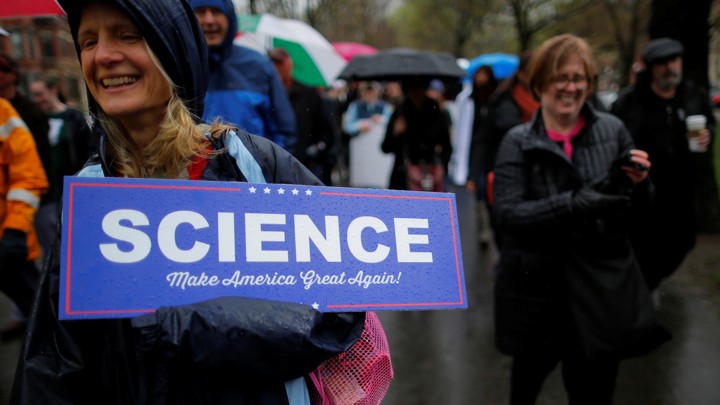 A woman at a rally holds a sign that says "Science: Make America Great Again!"