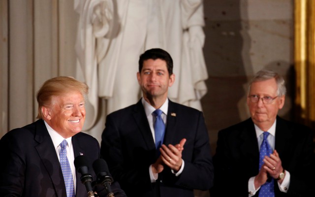 President Donald Trump smiling while Paul Ryan and Mitch McConnell clap
