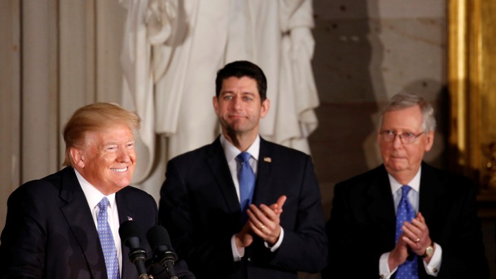 President Donald Trump smiling while Paul Ryan and Mitch McConnell clap