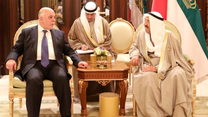 Iraq's prime minister, who is dressed in a suit, talks to the emir of Kuwait, who is dressed in traditional clothes.