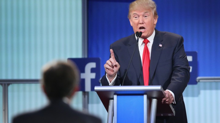 Donald Trump speaks at a podium next to a Facebook logo.