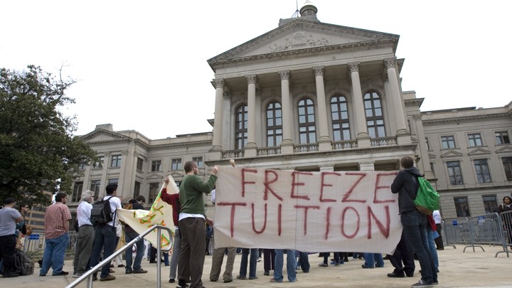 Students and alumni hold a sign that reads "Freeze Tuition."